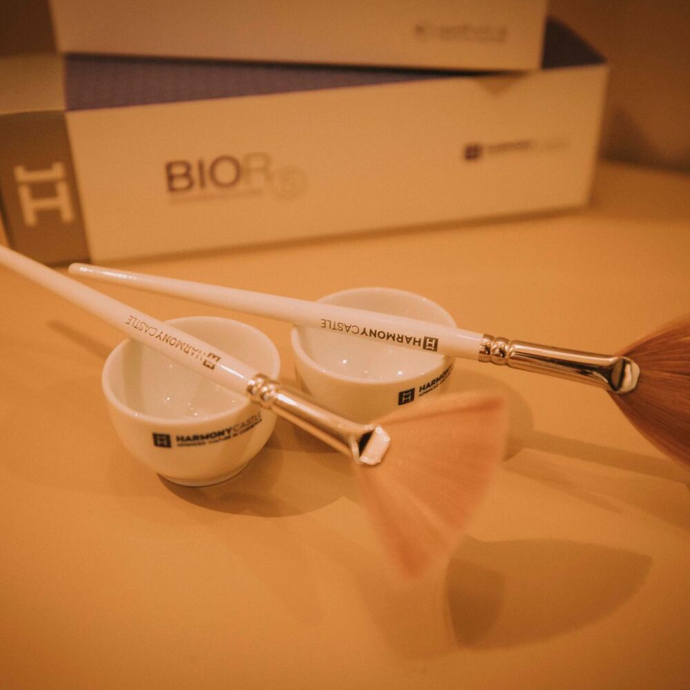 Due pennelli per il trucco sono appoggiati su un tavolo davanti a una scatola con la scritta biore