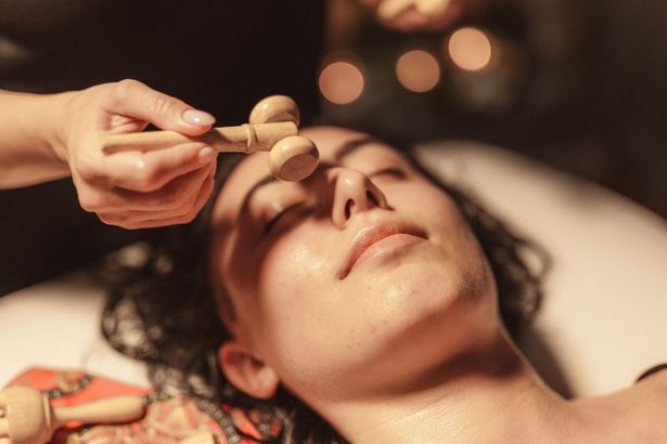 Una donna si sta facendo massaggiare il viso con dei bastoncini di legno.