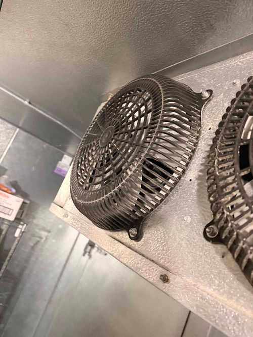 Two metal fan guards mounted on a refrigerator wall.