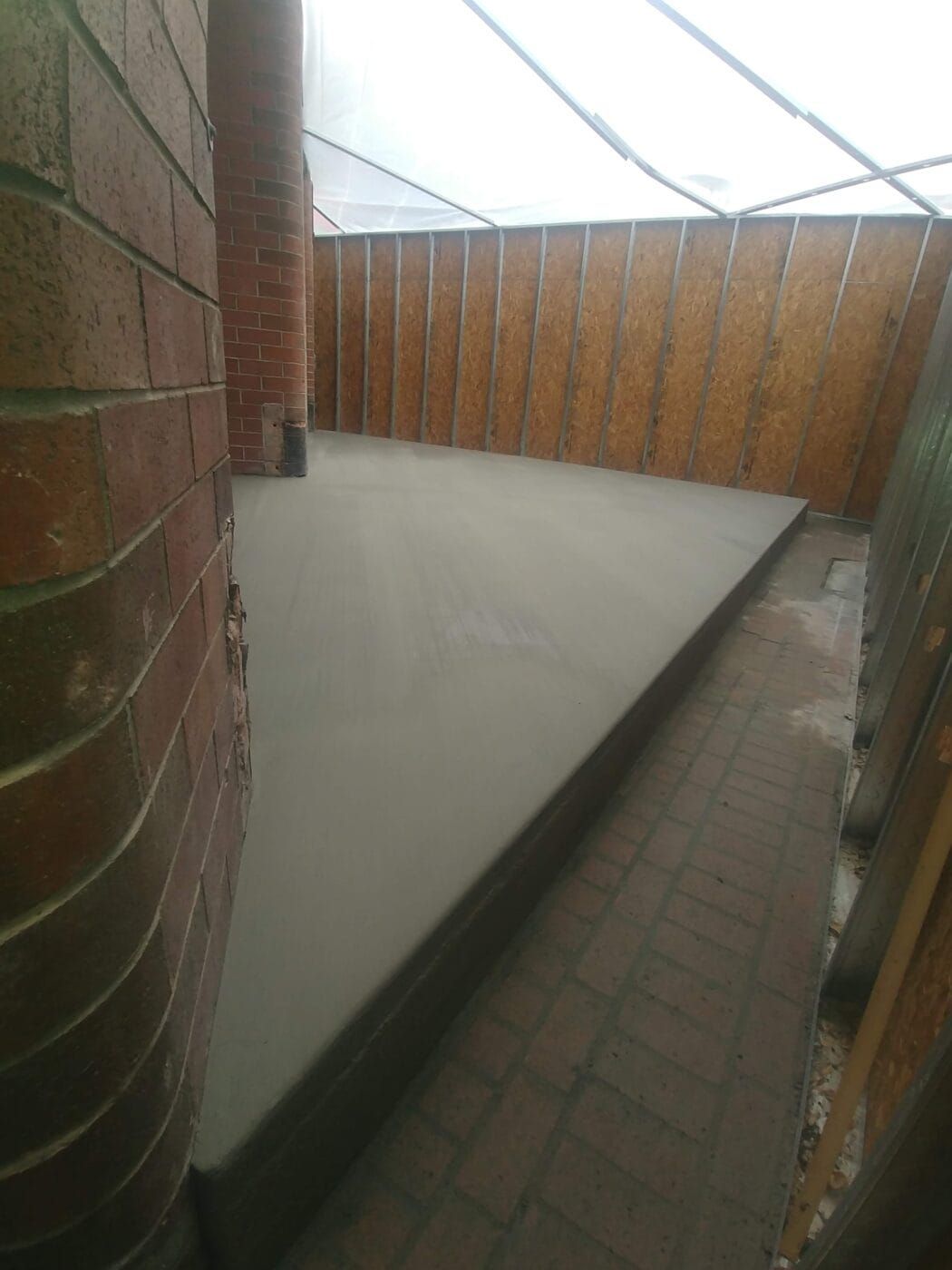 A brick wall with a concrete floor in the middle of it.