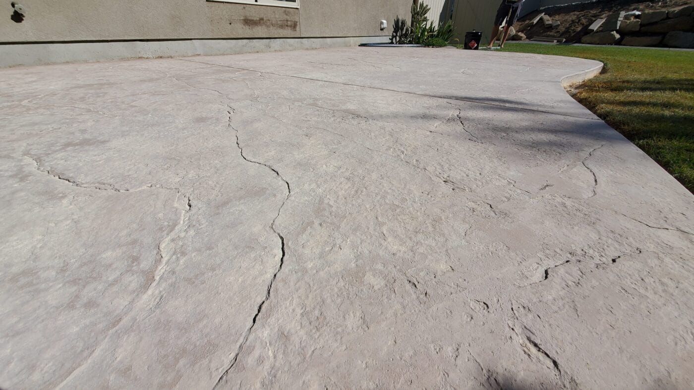 A concrete driveway with a swirl pattern and a house in the background.