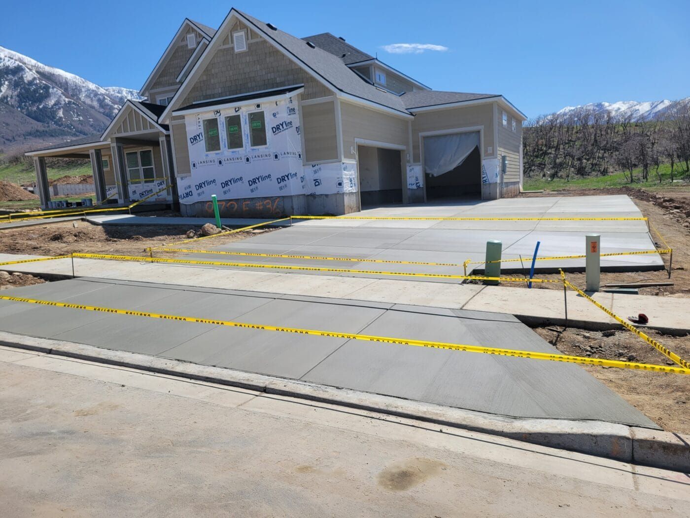 A house under construction with a concrete driveway in front of it