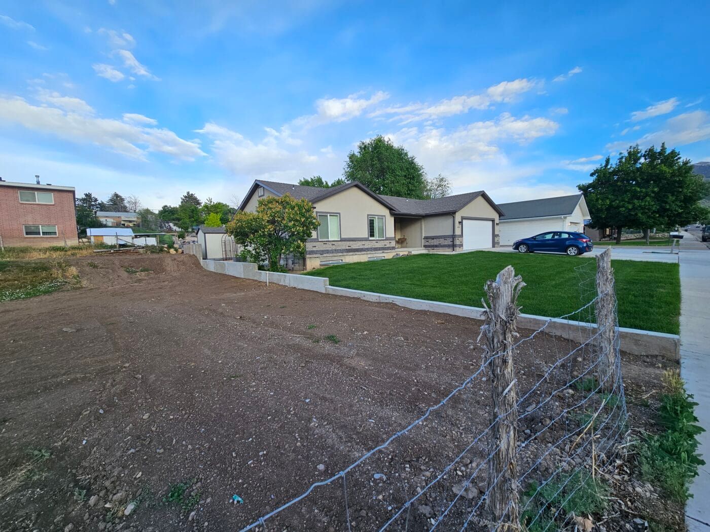 A house is sitting on top of a dirt field next to a barbed wire fence.