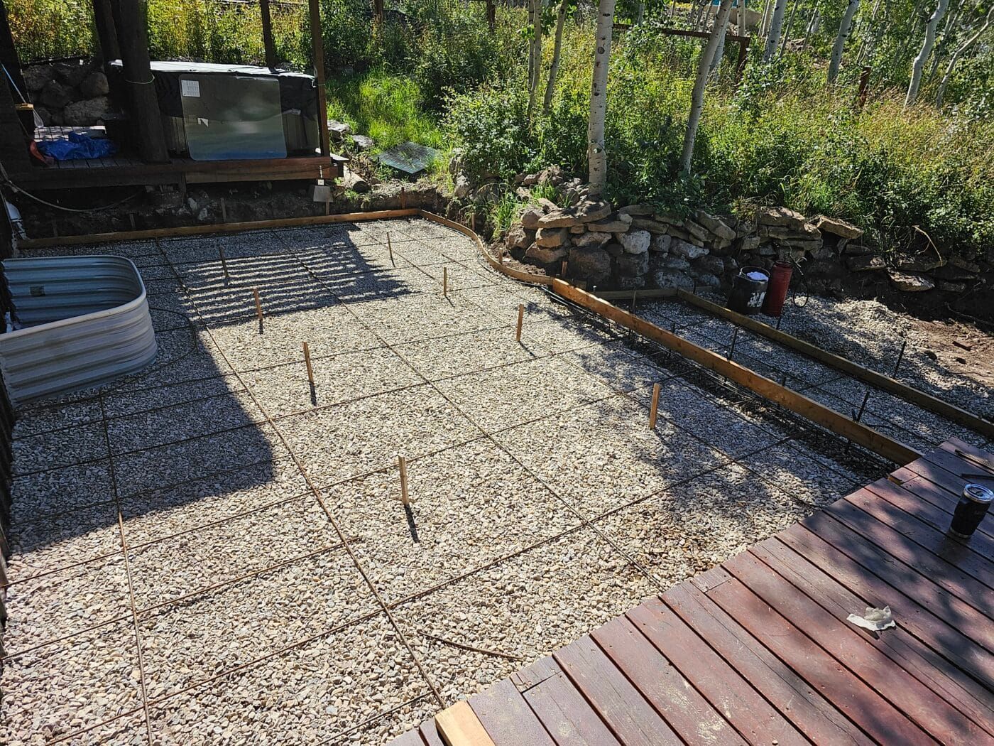 A wooden deck is sitting on top of a gravel patio.