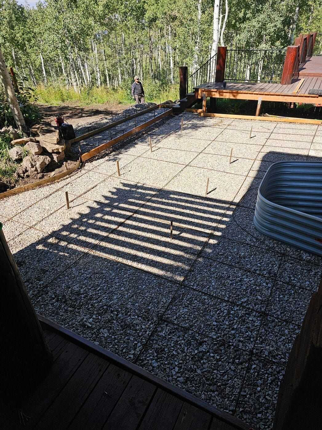 A concrete patio is being built in the woods with trees in the background.