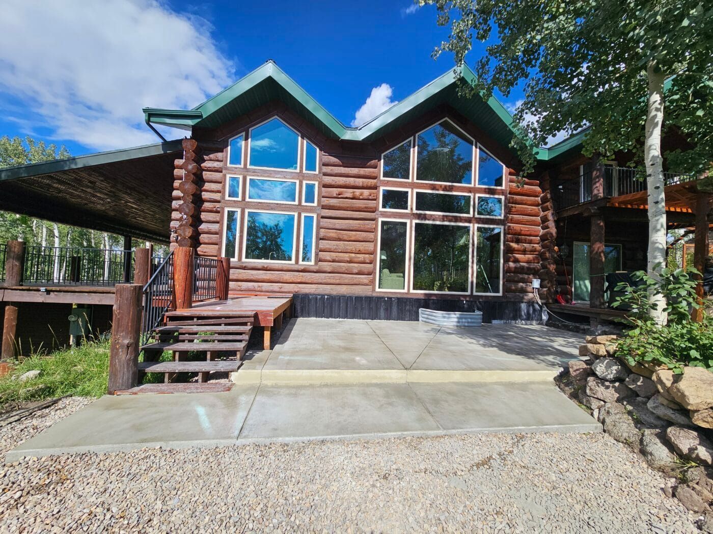 A large log cabin with a concrete driveway leading to it.