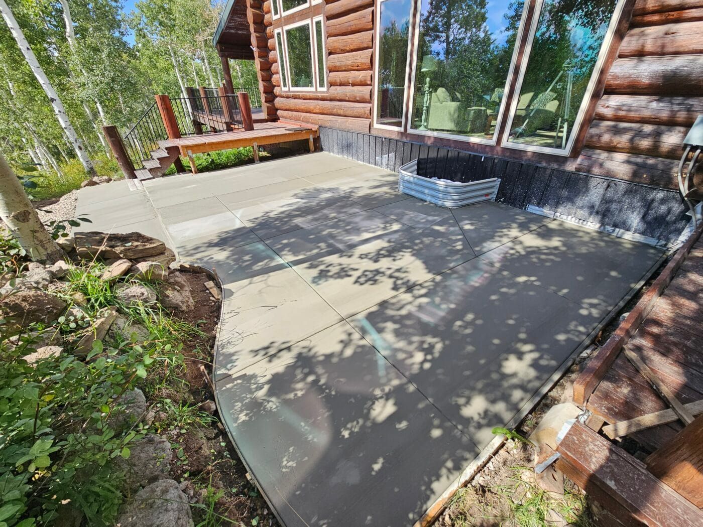 A concrete patio is being built in front of a log cabin.