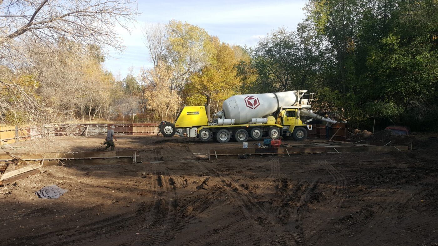 A concrete mixer truck is parked in a dirt field.