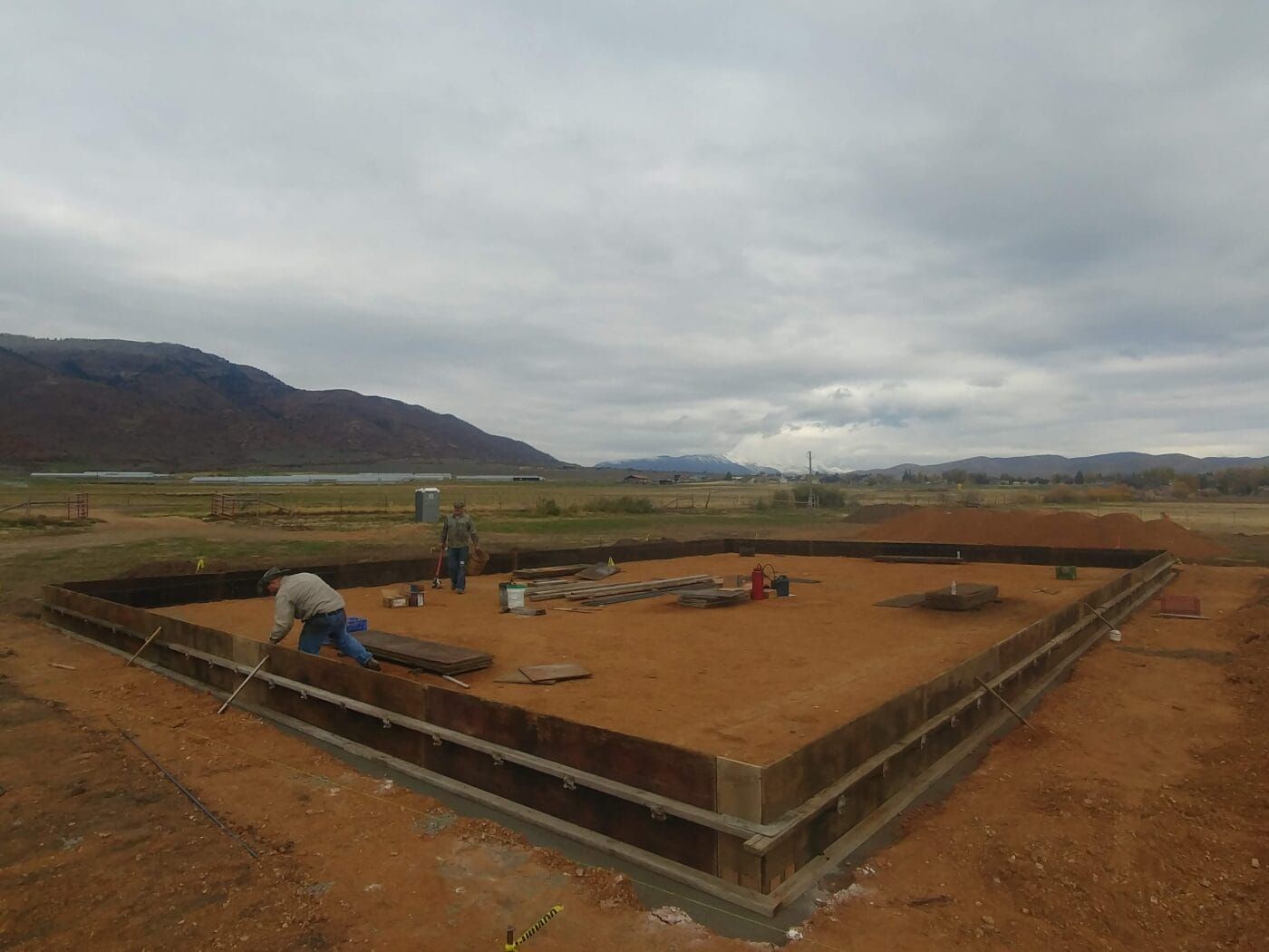 A group of people are working on a construction site with mountains in the background.