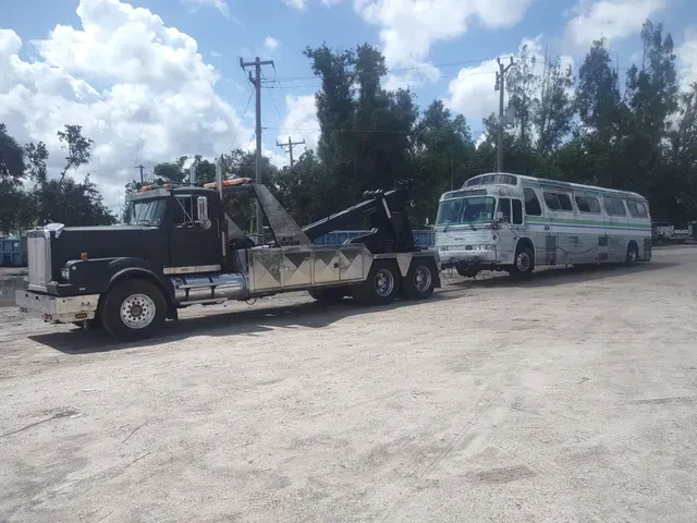 a tow truck is towing a bus in a parking lot