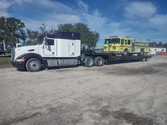 a white semi truck is towing a yellow fire truck