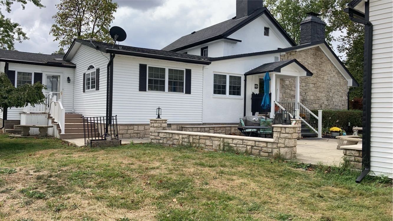 A white house with a stone patio in front of it.
