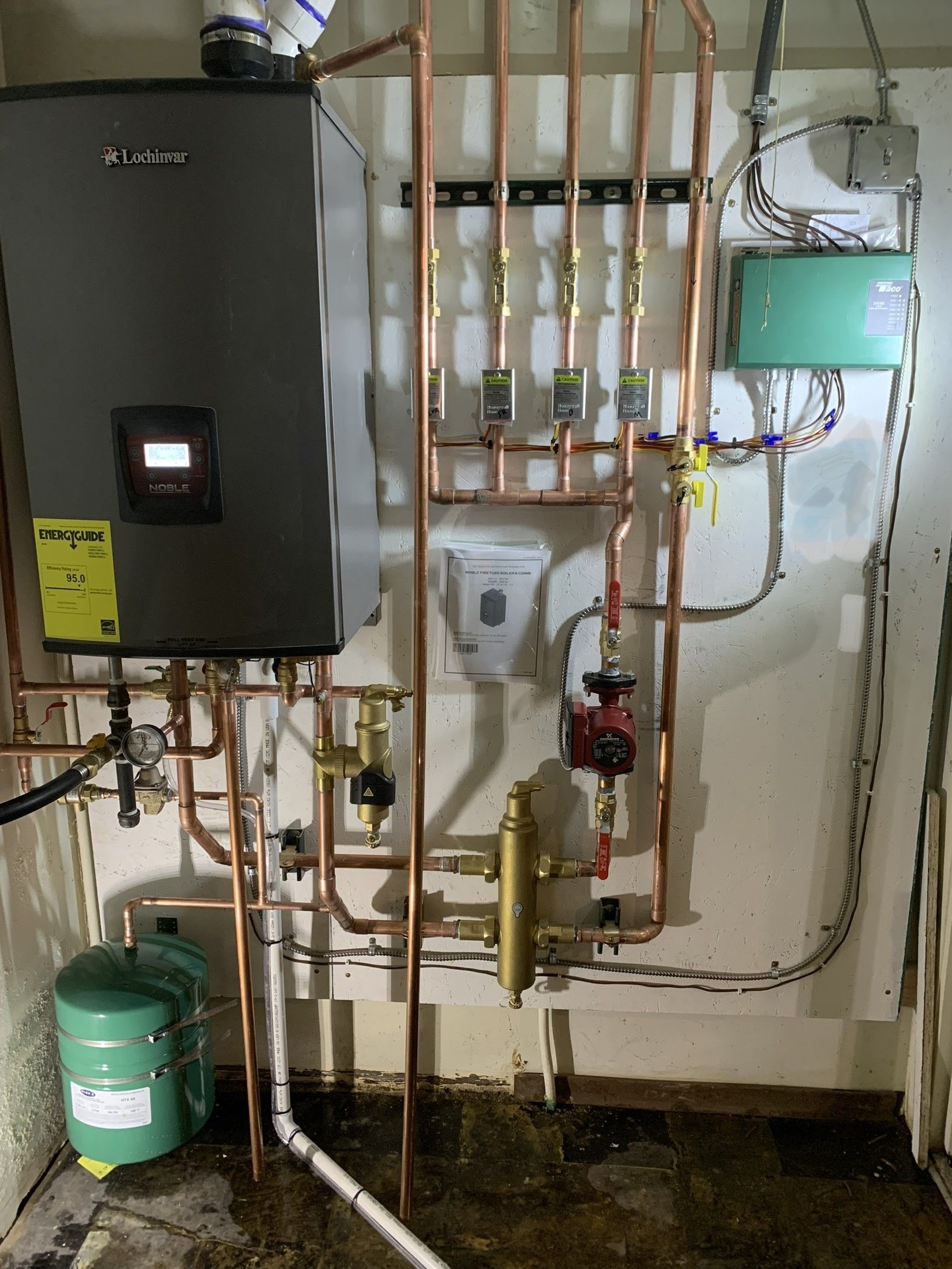 Copper pipes and heating system components mounted on a wall in a utility room.