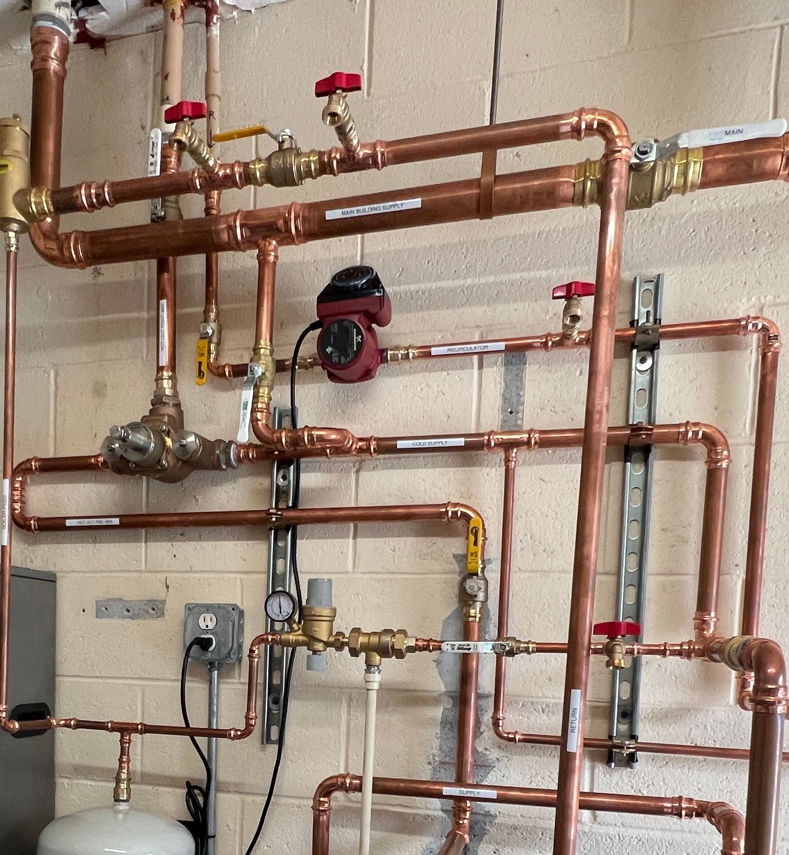 Copper pipes and valves, part of a heating system, mounted on a wall.