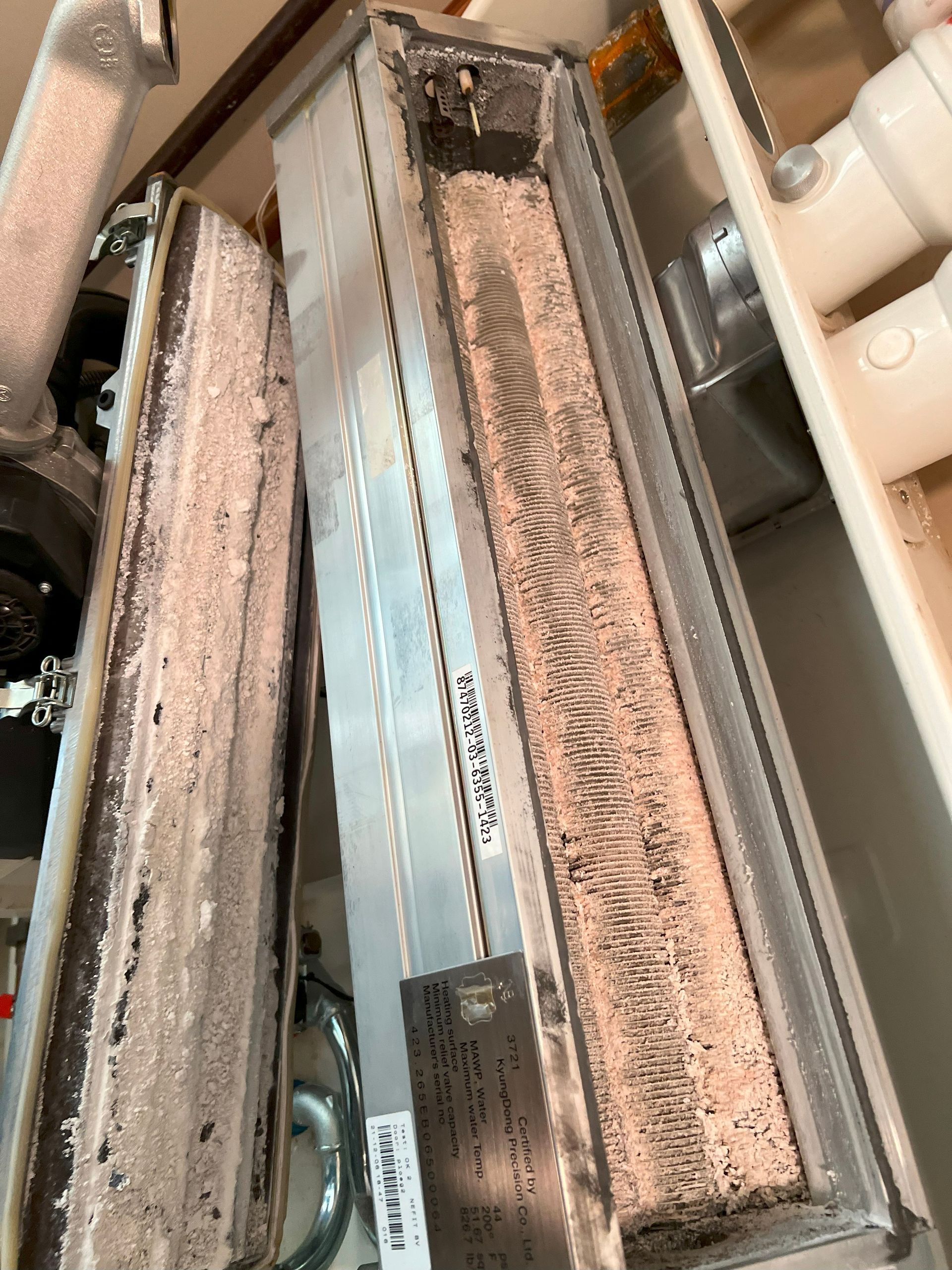 Two long, rectangular air filters with significant dust buildup inside a ventilation system.