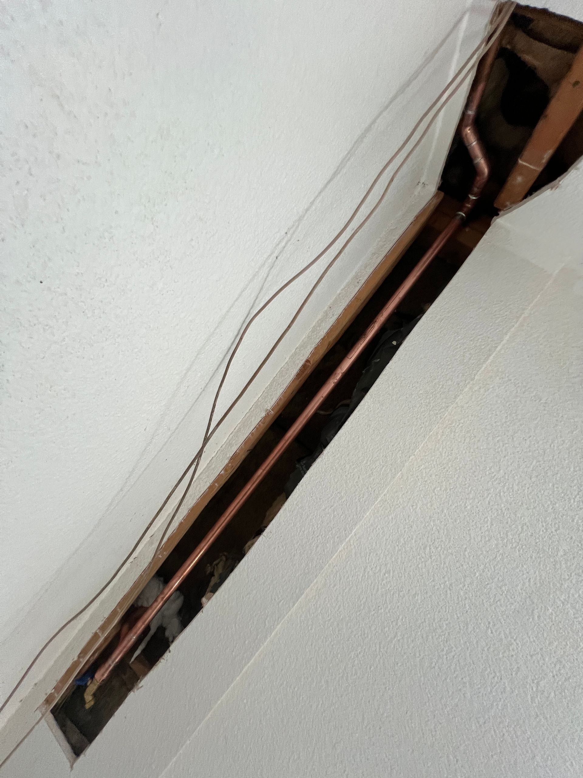 A flexible circuit encased in clear tape, with thin wires and copper-colored pathways on a white surface.