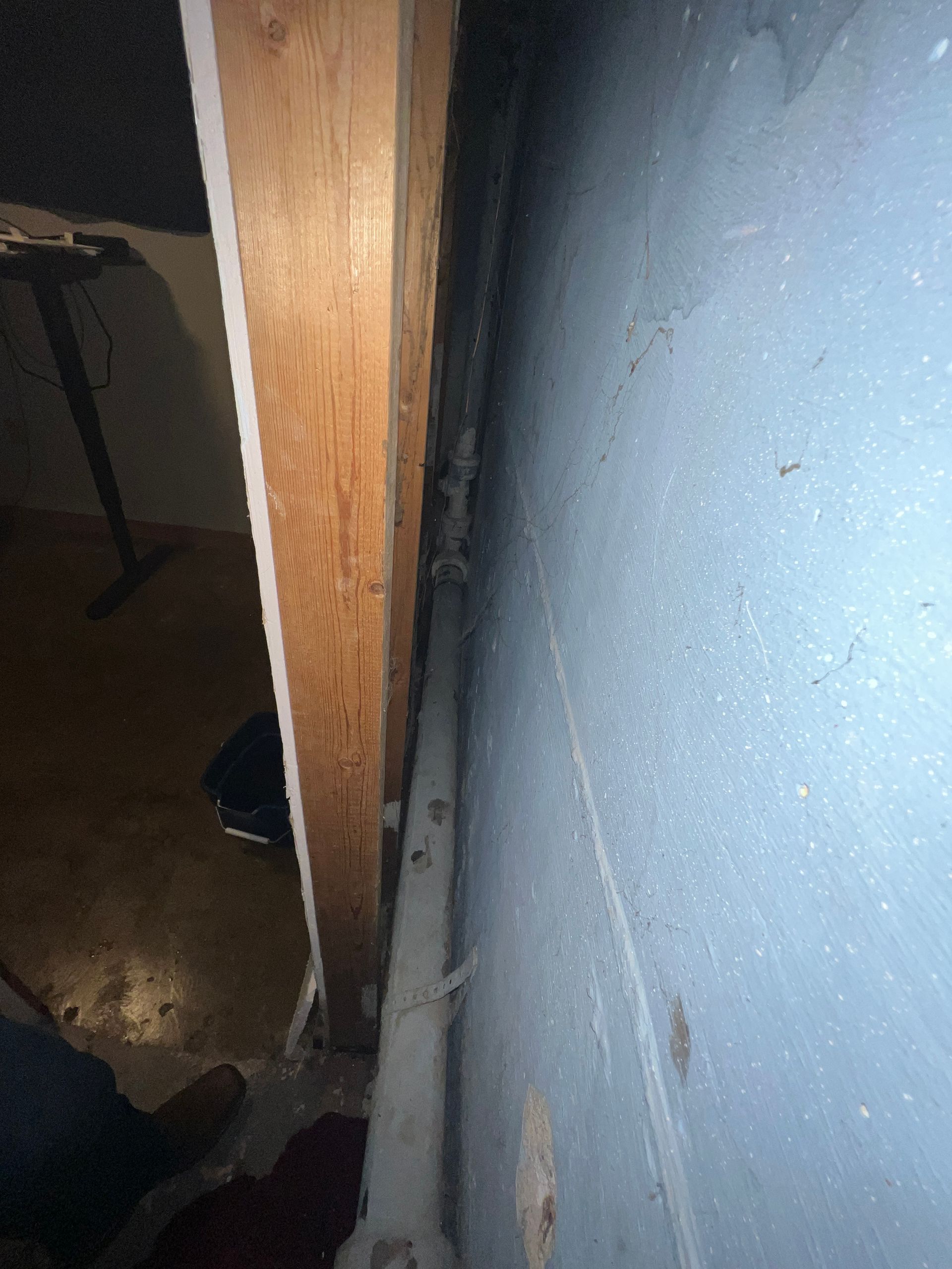 Wooden door frame next to a blue wall with a pipe running along the base.