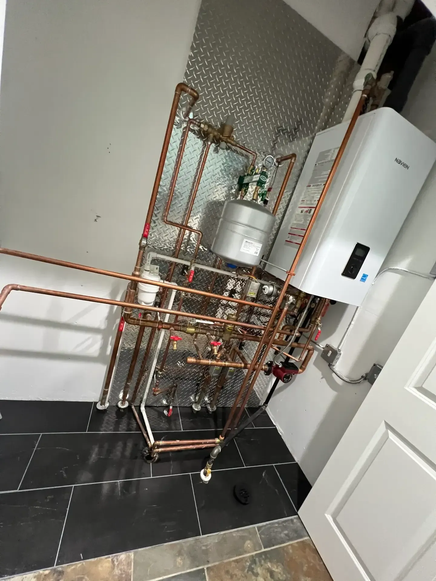 Copper pipe plumbing system with a water heater installed on a wall.