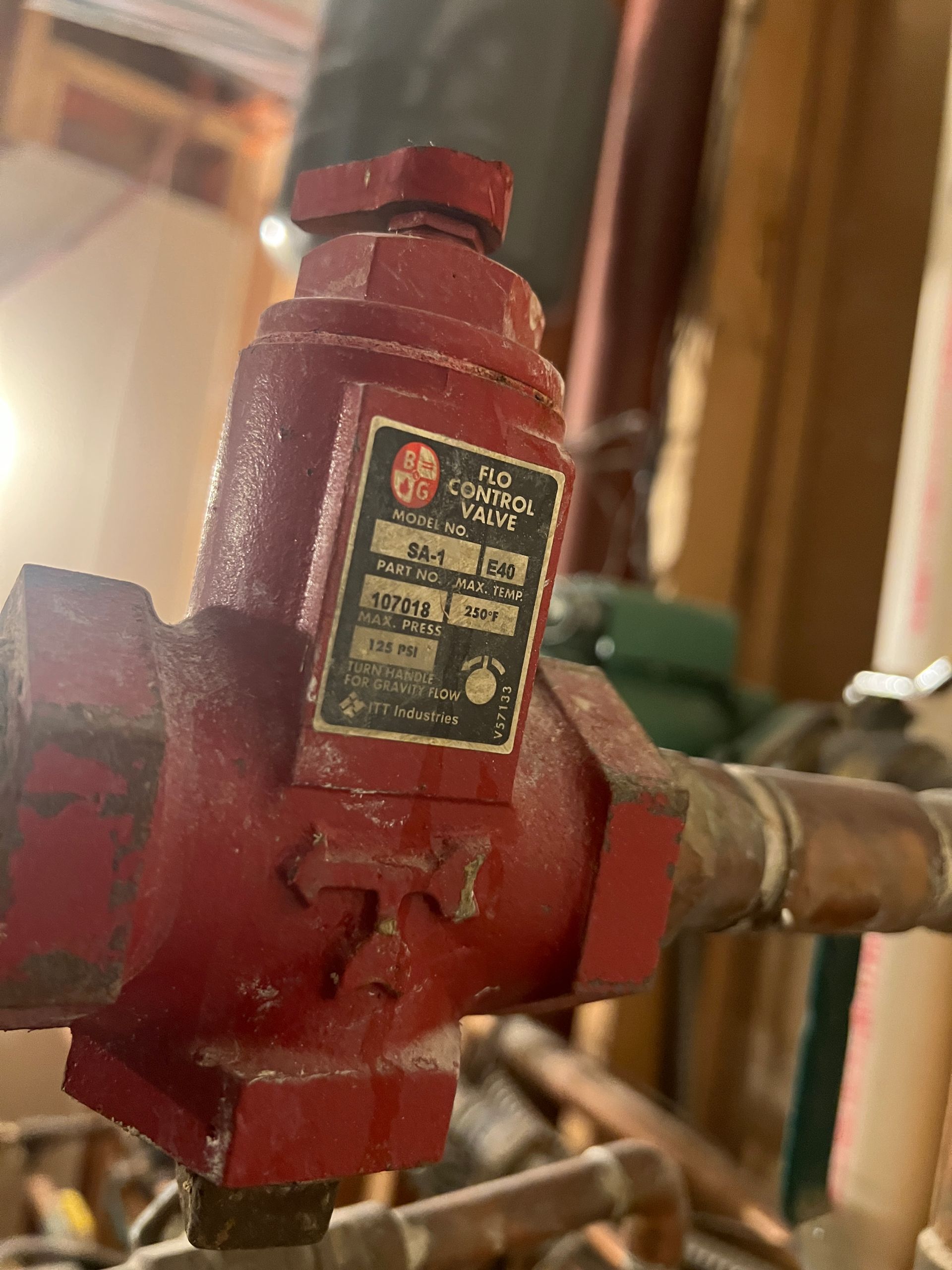 Red heating control valve with label attached to copper piping.