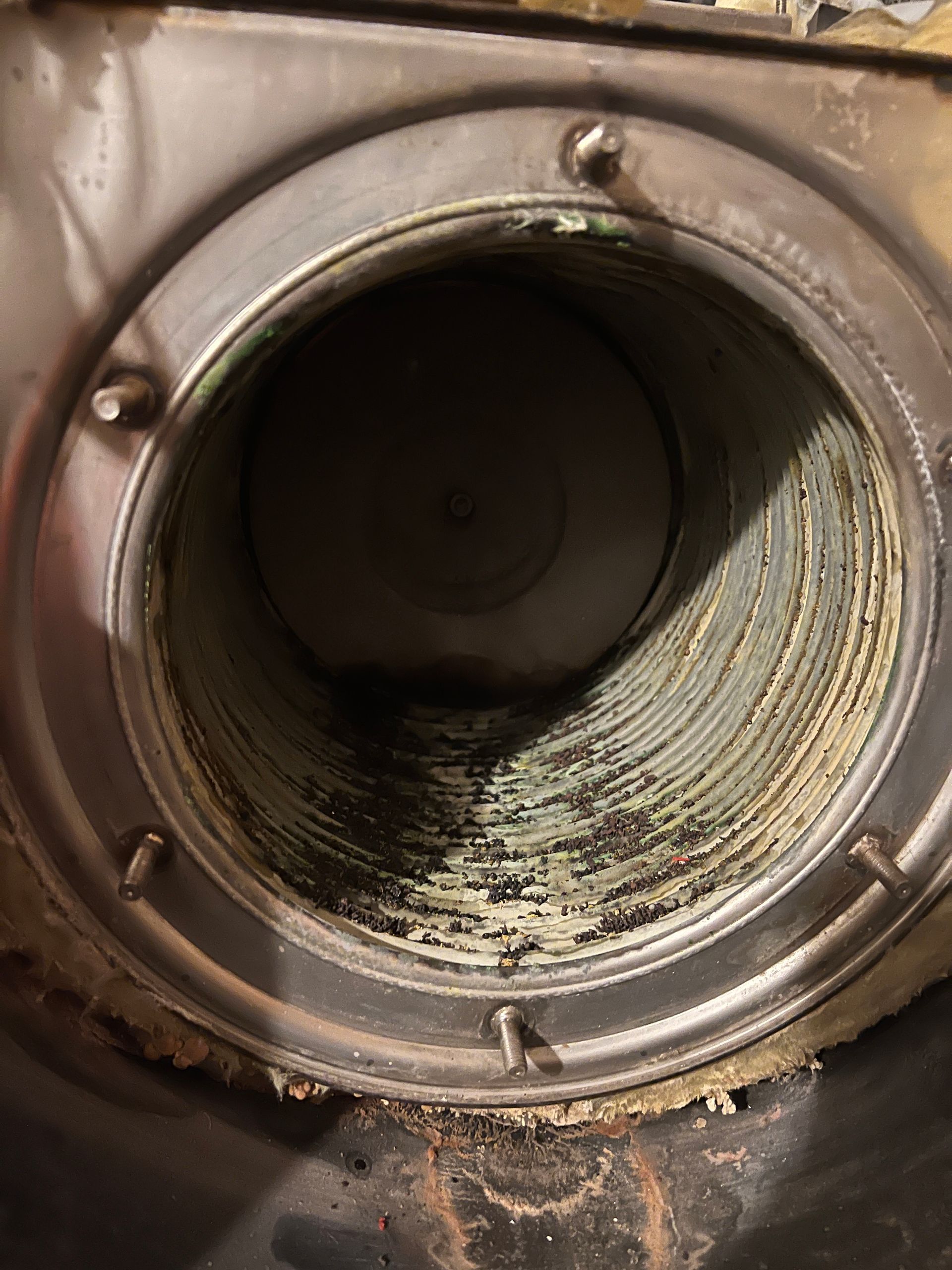 Inside view of a metal furnace flue pipe with layers of buildup.