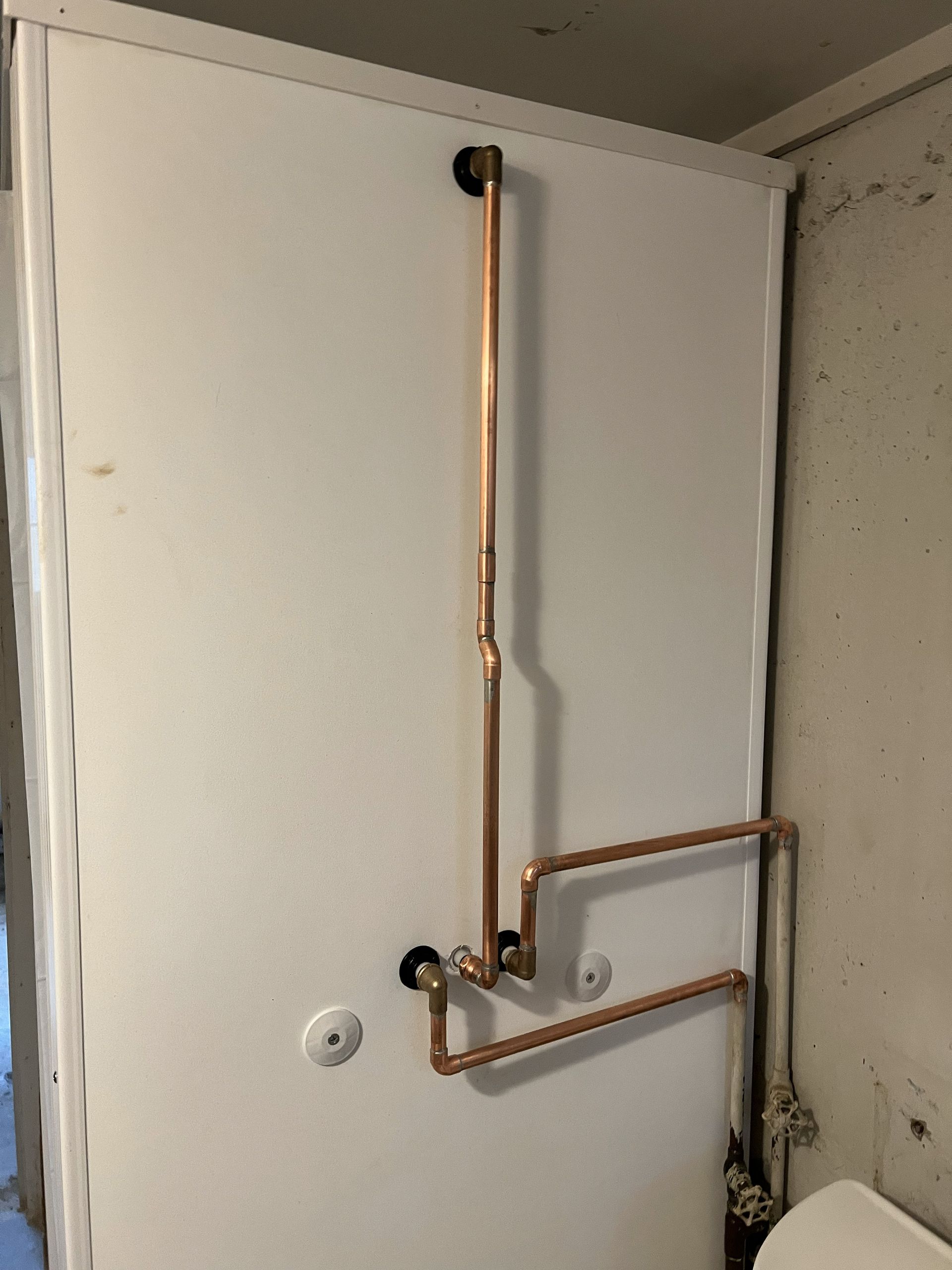 Copper pipes mounted on a white wall.