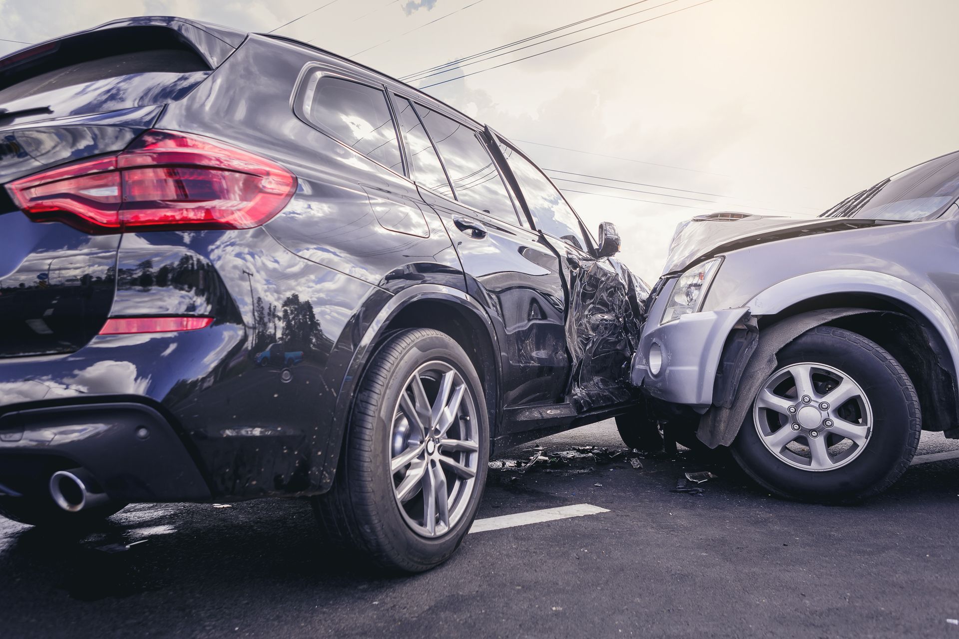 An SUV and a car crashing on an asphalt road.