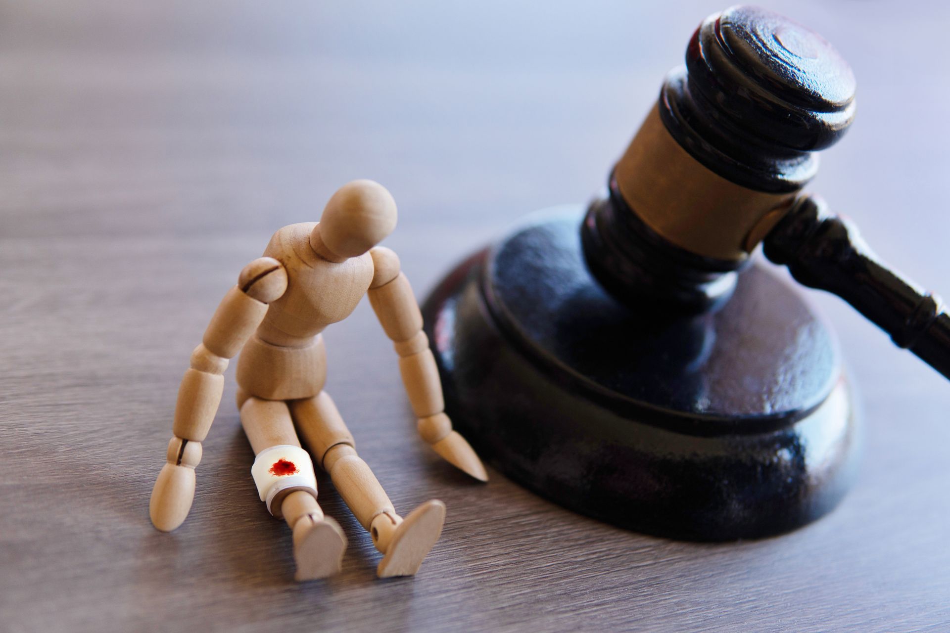 A wooden doll with a bandage wrap next to a wooden gavel on a workers' compensation lawyer's desk.