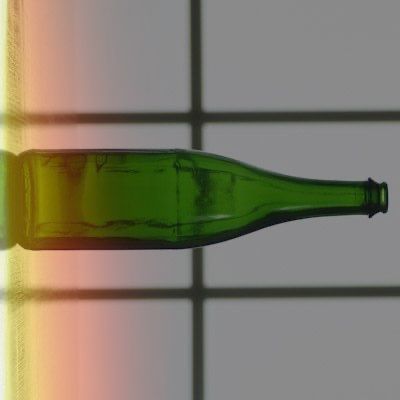 A green bottle is sitting on a tiled floor next to a window.
