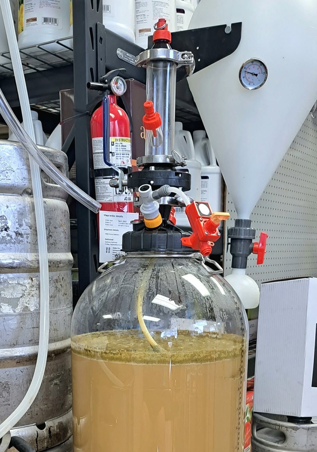 A bottle of liquid is sitting in a warehouse next to a fire extinguisher.
