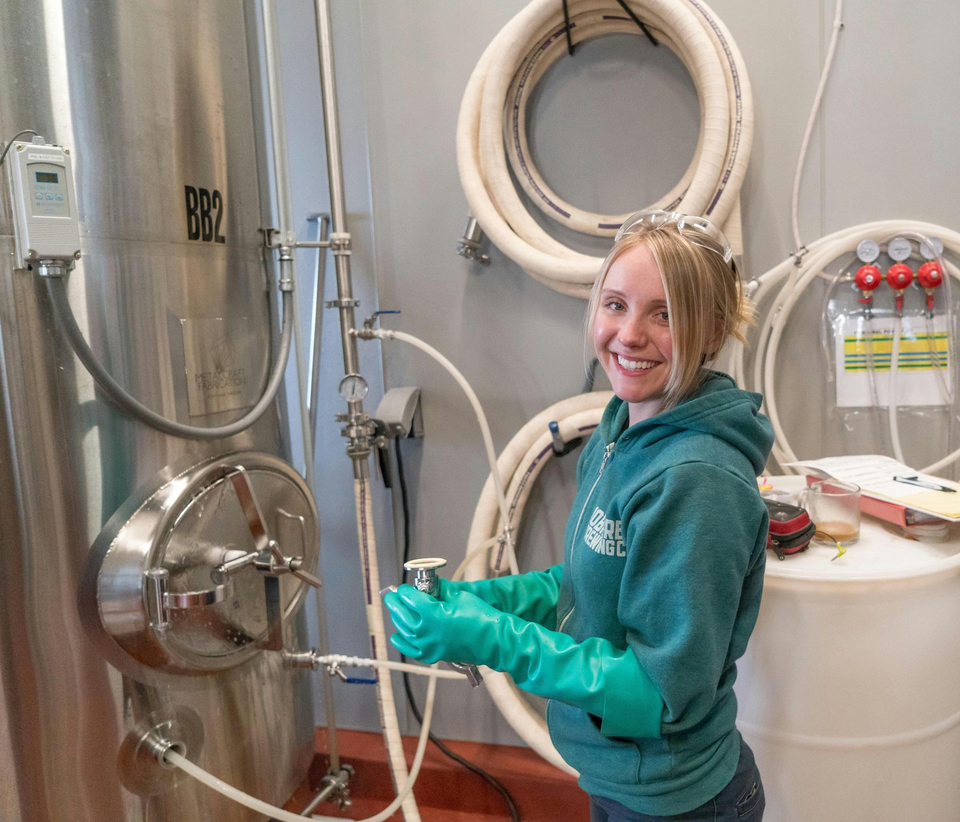 A woman wearing green gloves is smiling in front of a tank that says brl