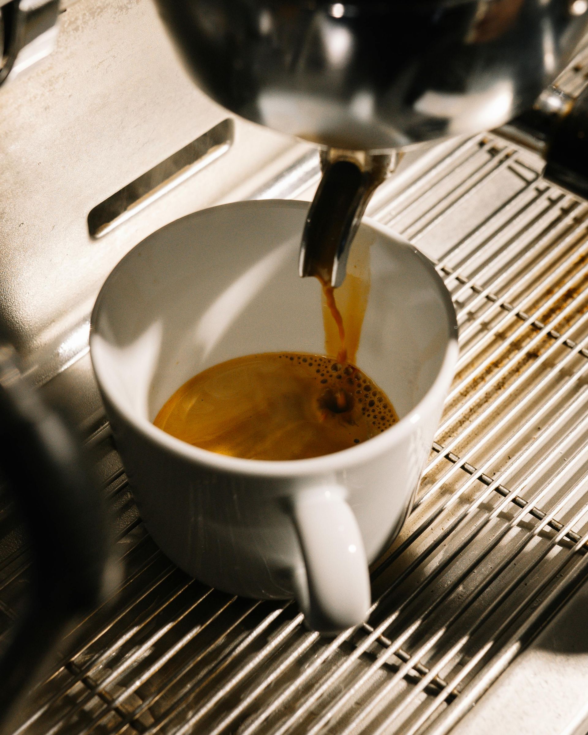 A cup of coffee is being poured into a machine