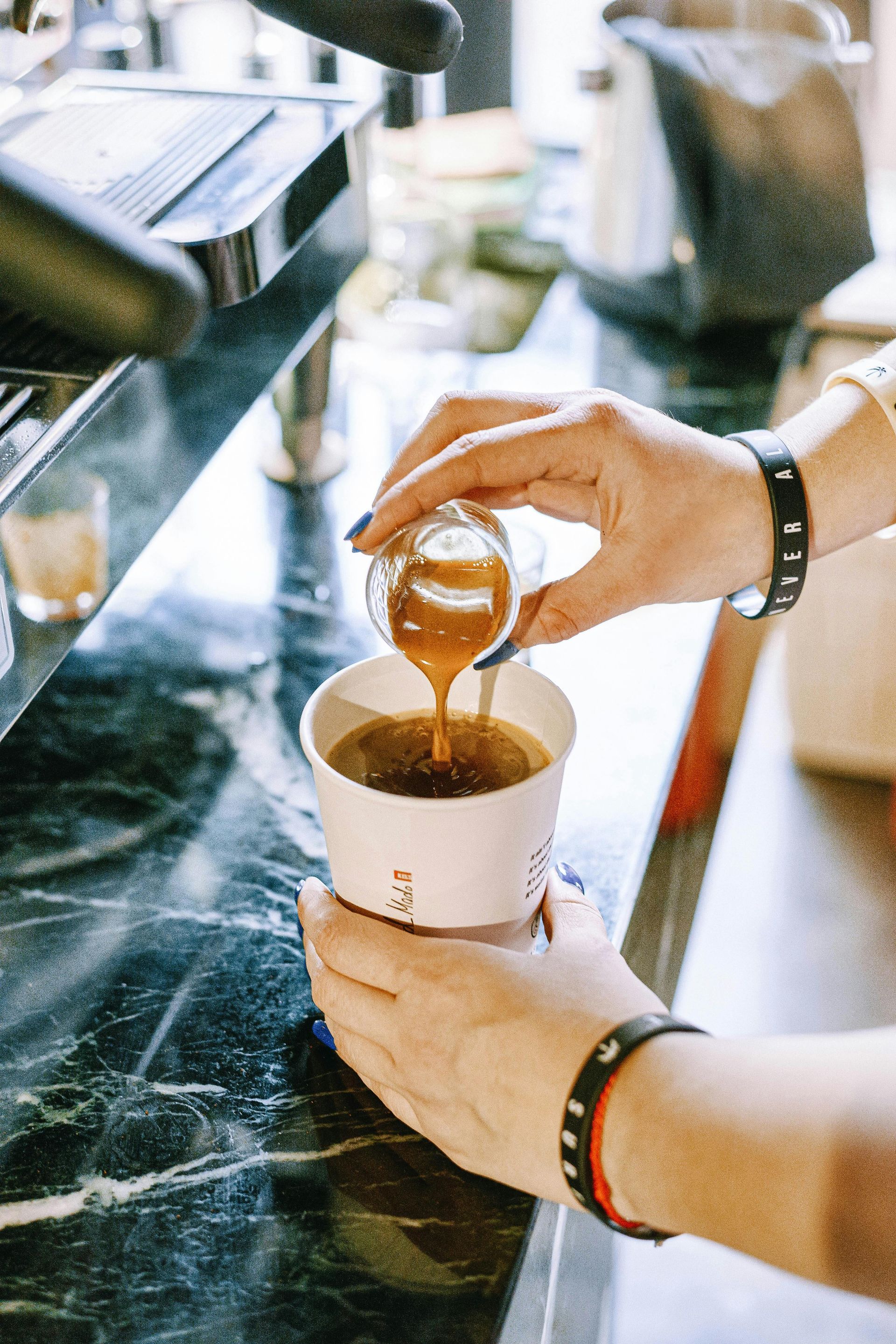A person is pouring liquid into a cup of coffee.