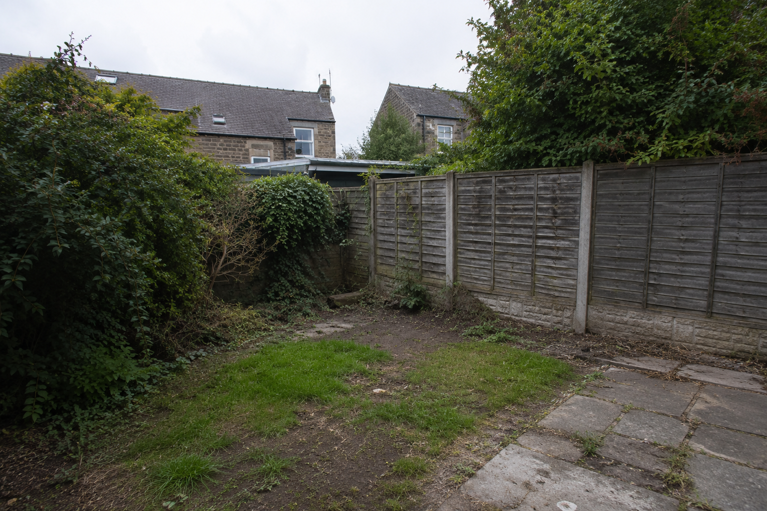 Curved driveway lined with manicured shrubs leading to a large house with a steep roof.