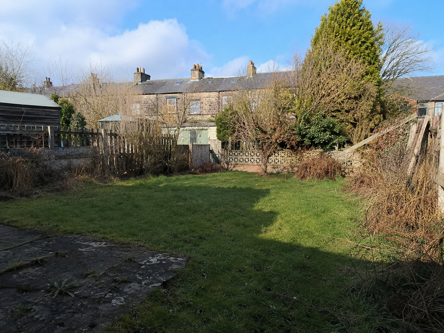 Curved driveway lined with manicured shrubs leading to a large house with a steep roof.