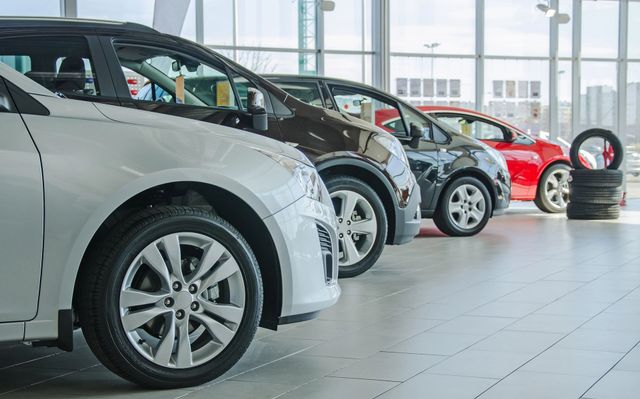 Una fila di auto parcheggiate nello showroom luminoso di una concessionaria.