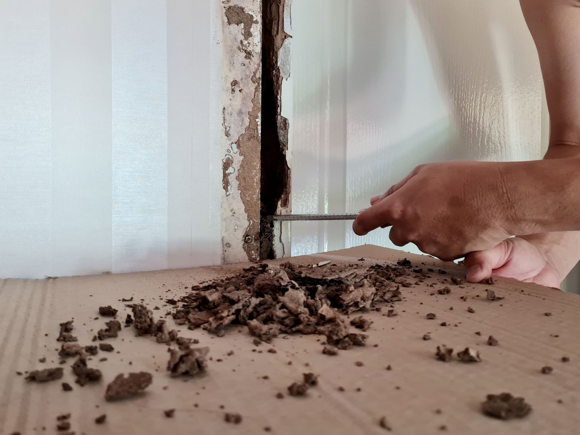 Woman in straw hat smiles, holding wine glass near a lake.