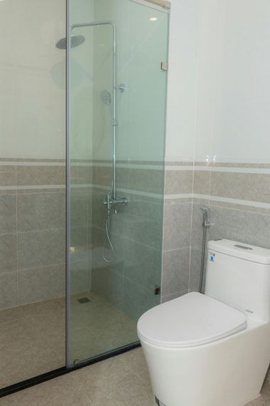 Compact bathroom with glass shower enclosure and white toilet beside a tiled wall.