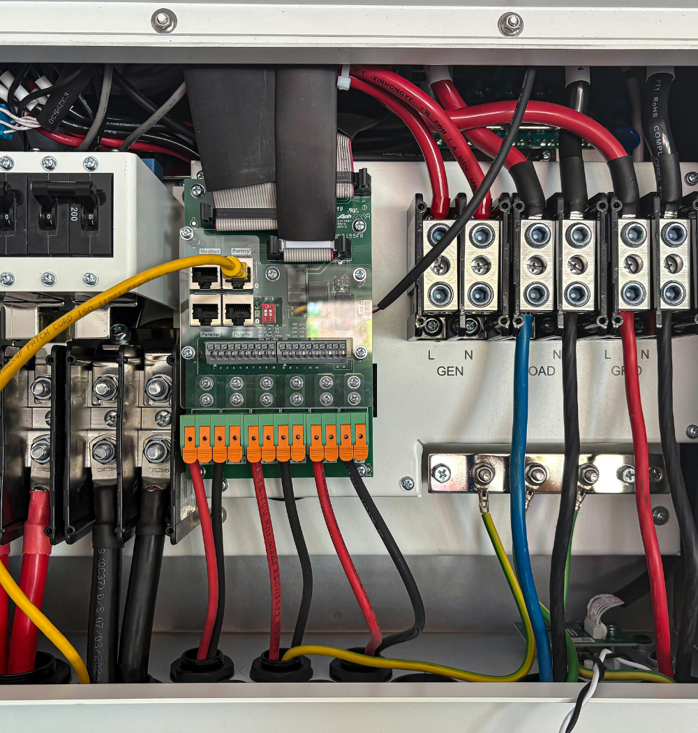Electrical panel with wires and circuit board. Red, black, yellow, and blue wires connect to terminals and other components.