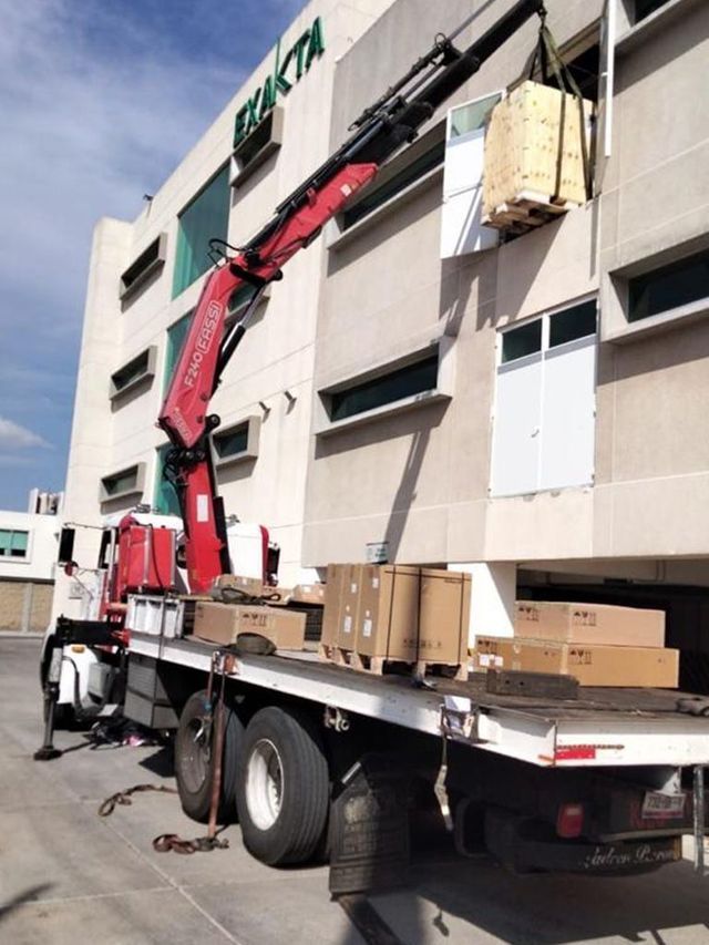 Un camión con una grúa acoplada está estacionado frente a un edificio que dice