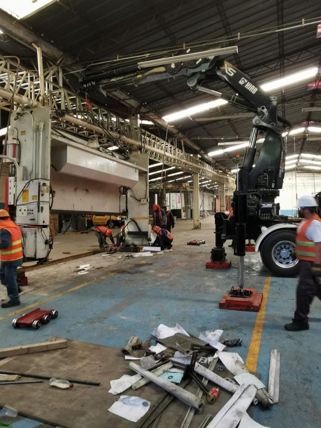 Un grupo de hombres está trabajando en un almacén con una grúa.