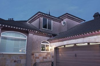 A large house with a garage and christmas lights on the roof.