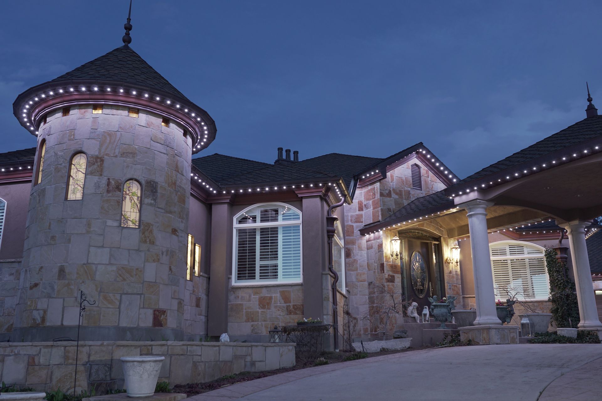 A large house with a castle shaped tower is lit up at night.