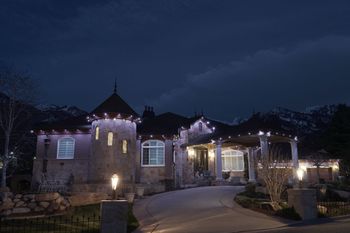 A large house is lit up at night with christmas lights.