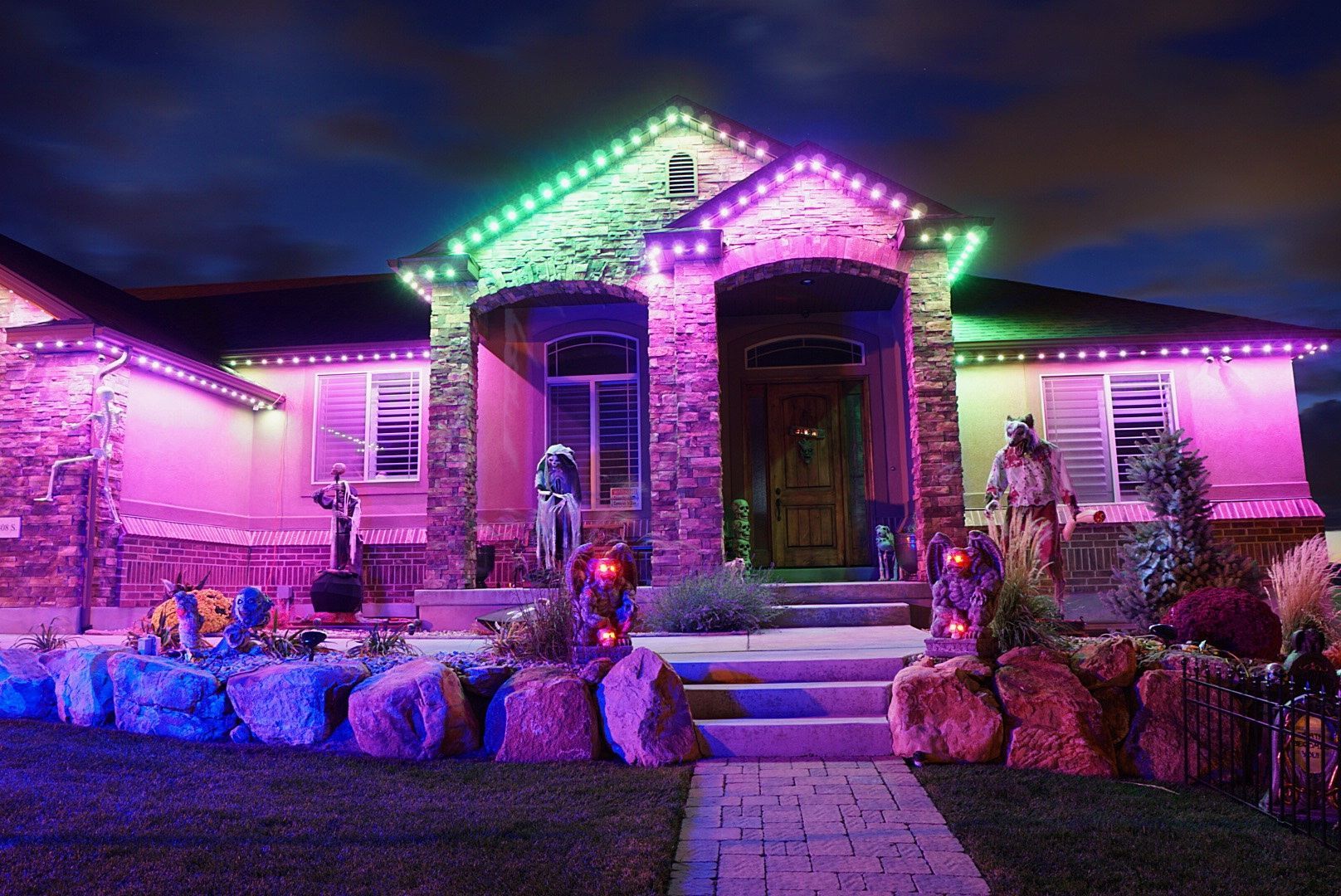 A house is decorated for halloween with purple and green lights.