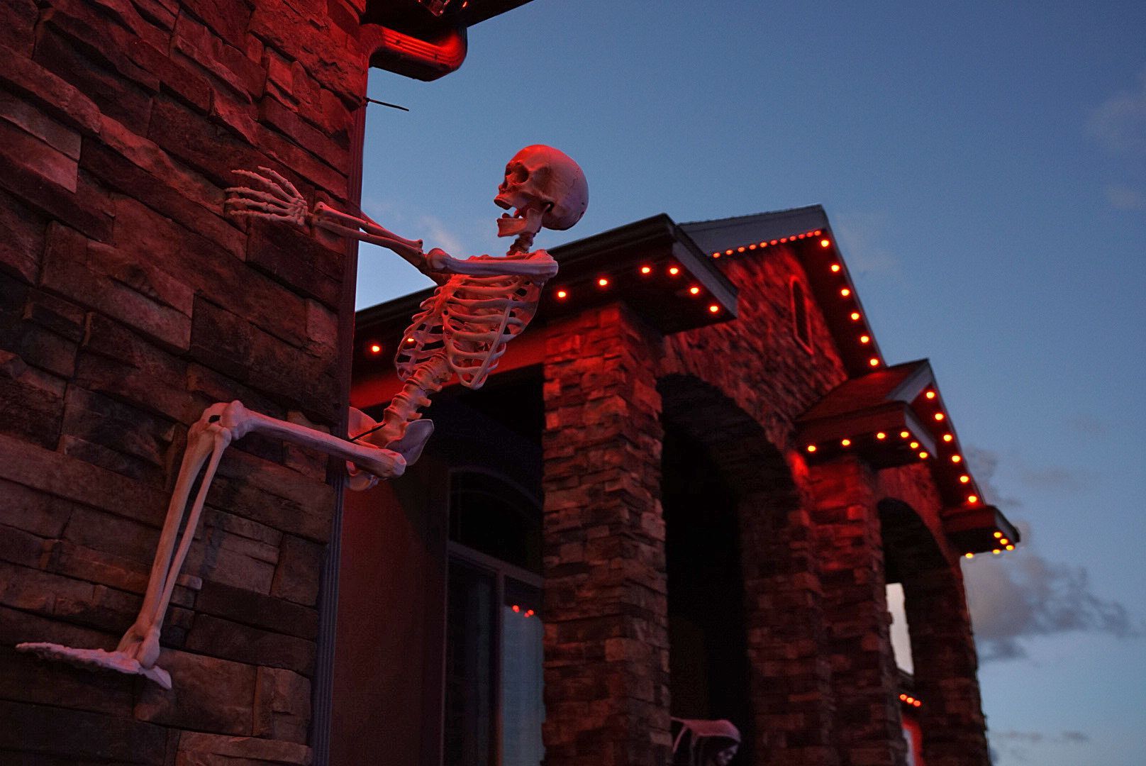 A skeleton is hanging from the side of a house.