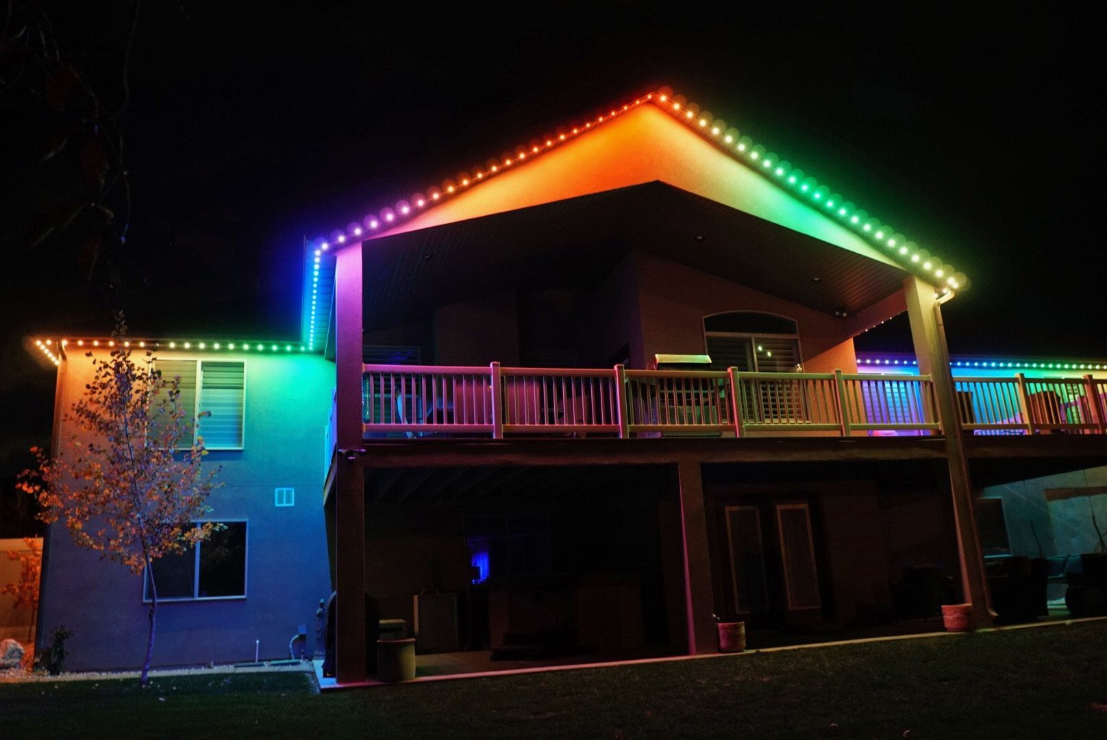 A large house is lit up with rainbow lights at night.
