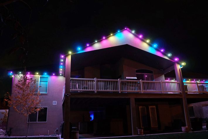 A house with a deck and christmas lights on it at night.