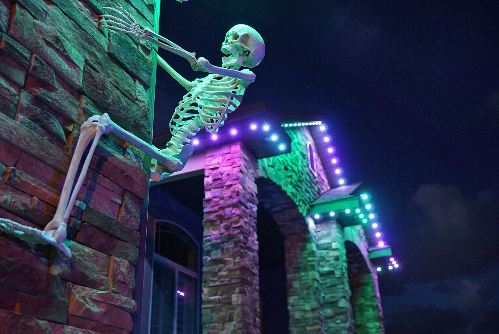 A skeleton is sitting on the side of a building.