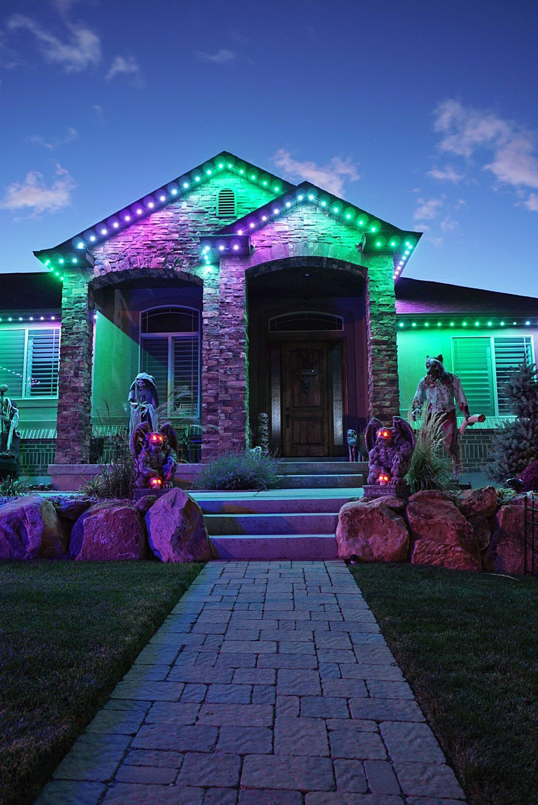A house is decorated with purple and green lights for halloween.