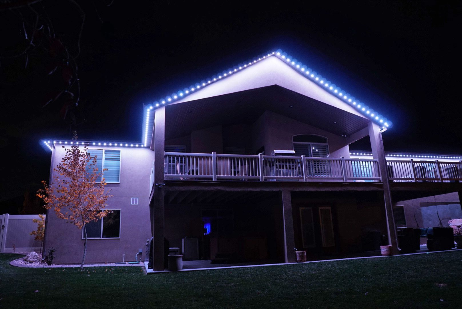 A large house with a large deck is lit up at night.